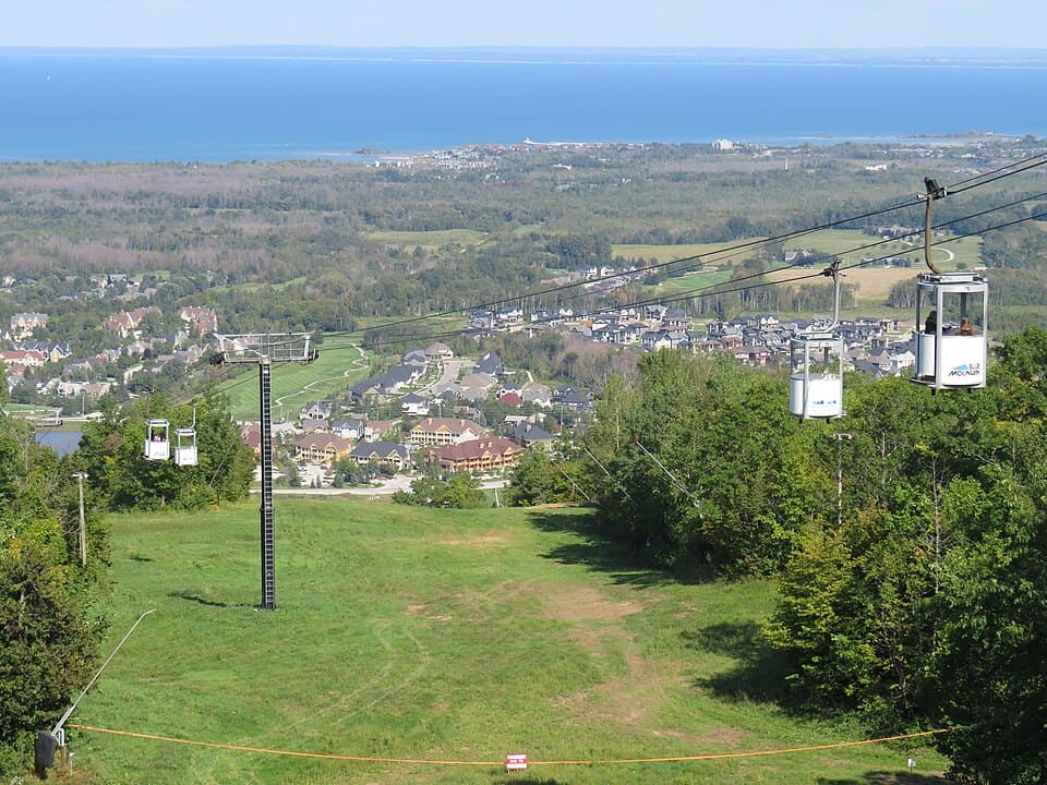 Cable cars over green slopes with a view of the village and bay at Blue Mountain, Canada. Scenic spot for a Blue Mountains guide.