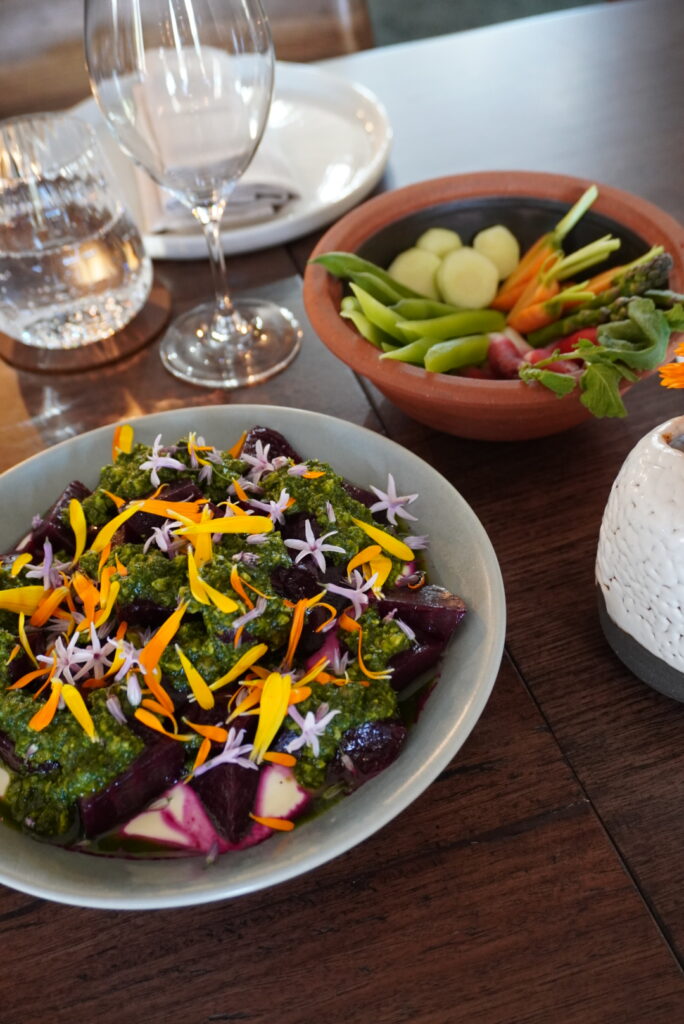Beetroot with herb sauce and flowers, with crudites and wine, on the table at Megalong