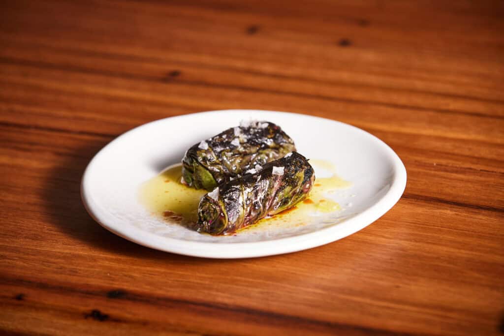 Delicious stuffed eggplant rolls served on a white plate with sauce.