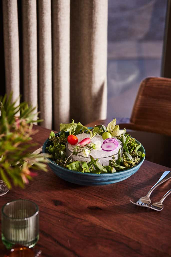 Fresh garden salad with radishes, onions, and greens on a dining table.