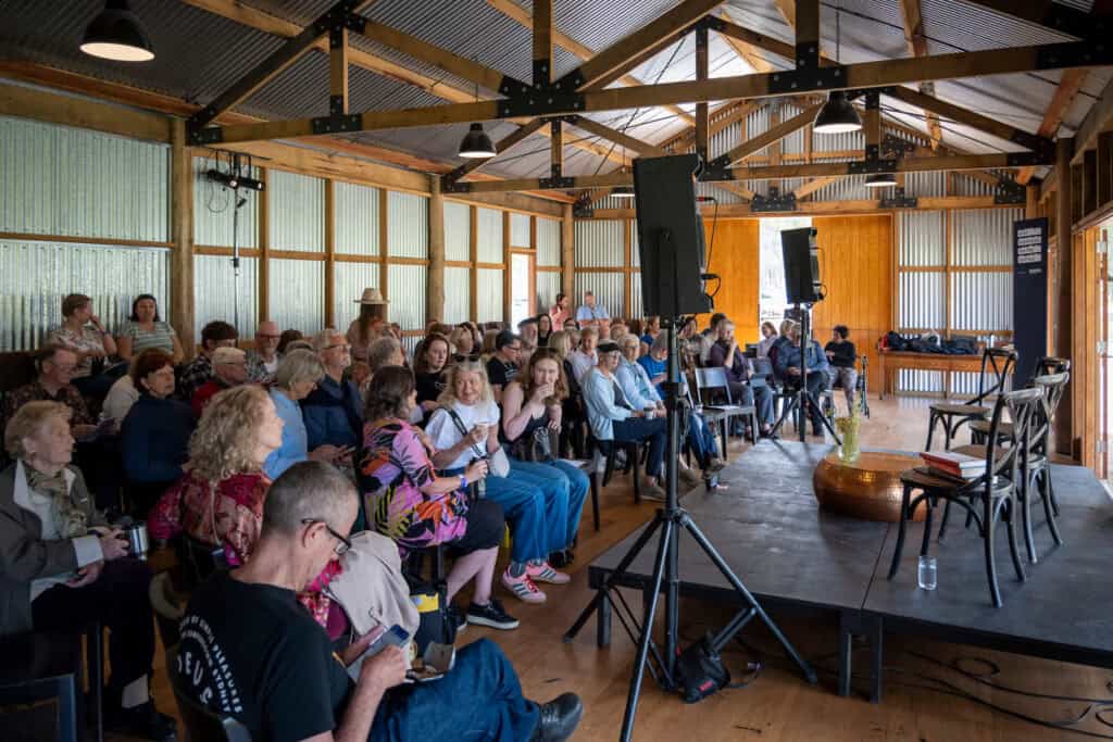 Audience attending a panel discussion at Lyrebird Festival 2026 in a rustic venue.