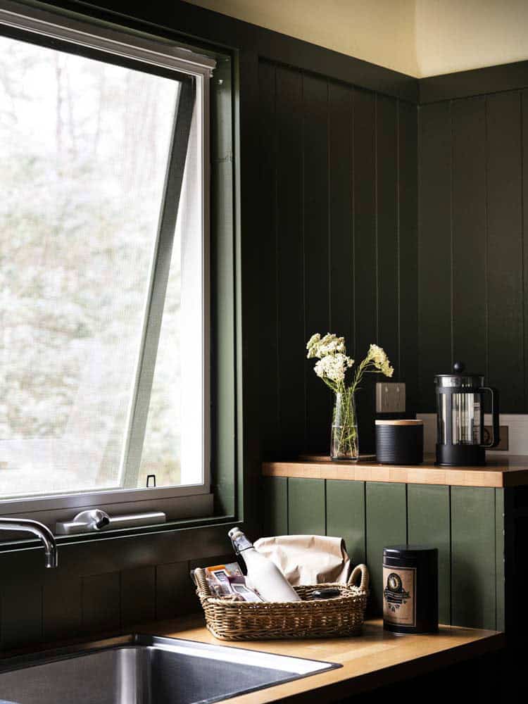 Contemporary kitchen interior with dark wall panels and a large window.