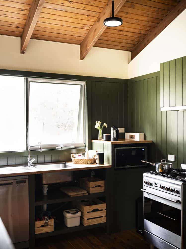 Kitchen interior with wooden ceiling, green wall panels, and modern appliances.