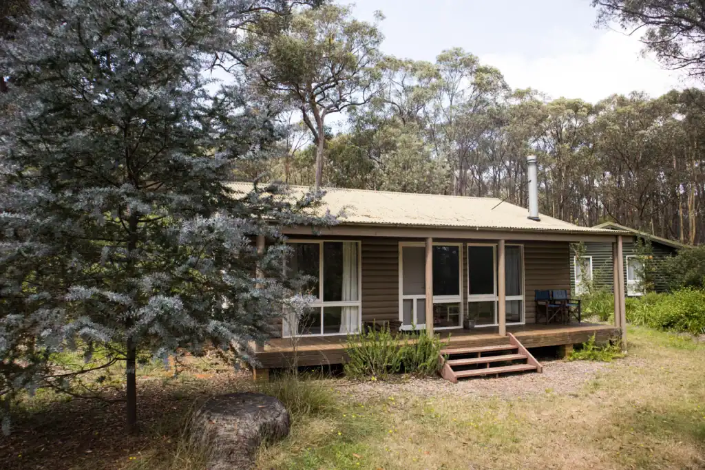 Cozy single-story house with a large front porch in a wooded area.