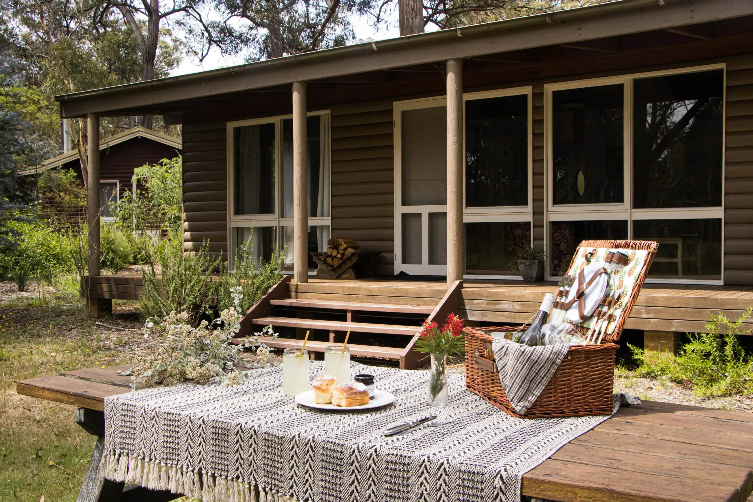 Charming cabin with outdoor deck, table, and garden setting for relaxation.