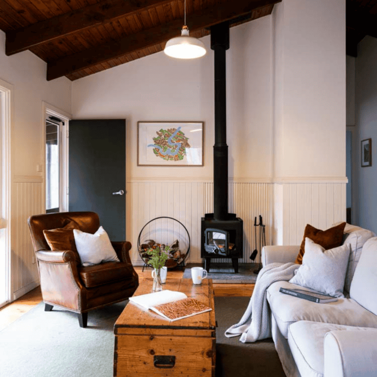 Warm living room with leather armchair, sofa, and wood stove for cozy ambiance.