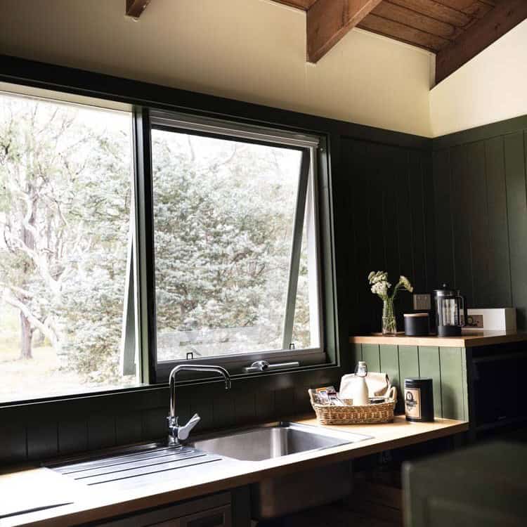 Contemporary kitchen with large open window and green wall paneling.