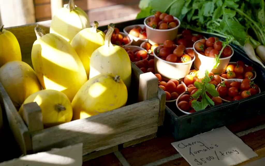 Fresh yellow pears and cherry tomatoes at a farm stand for sale.