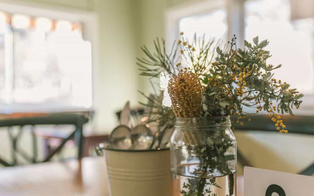 Decorative jar with greenery and dried flowers in a cozy kitchen setting.