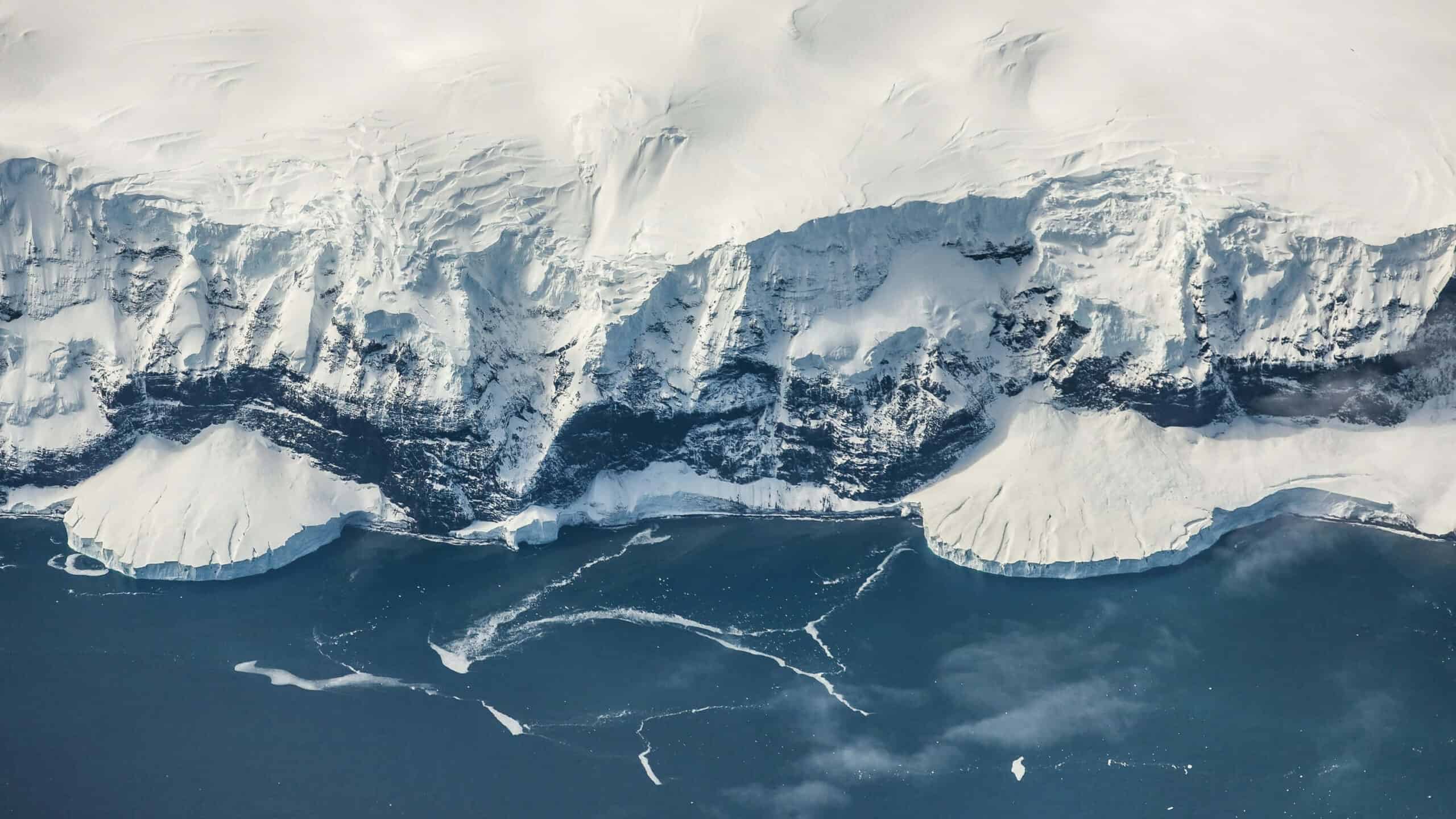 Aerial view of icy glacier with cracks and crevasses in the snow and ice.