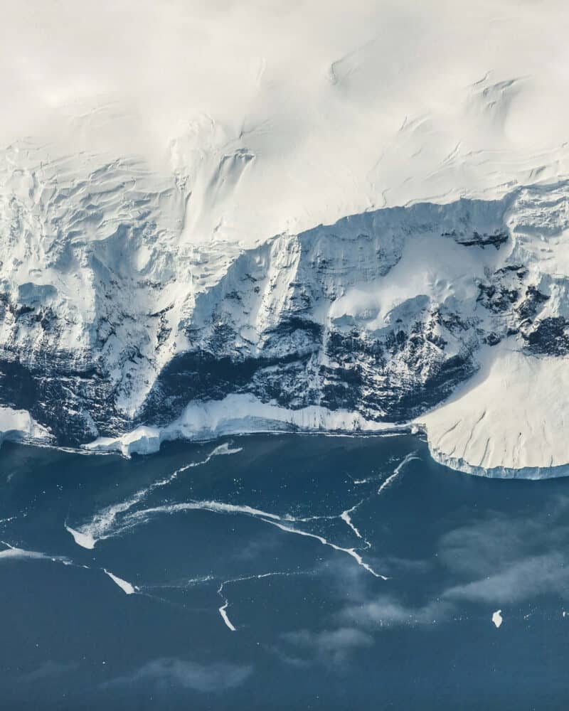 Aerial view of icy glacier with cracks and crevasses in the snow and ice.
