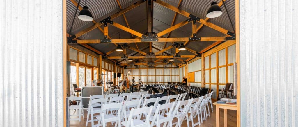 Spacious indoor event venue with wooden beams and seating arrangements.