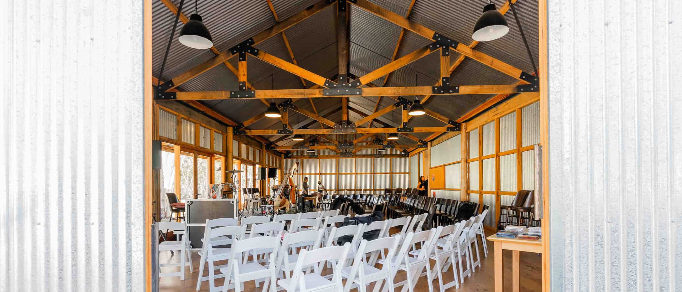 Spacious indoor event venue with wooden beams and seating arrangements.