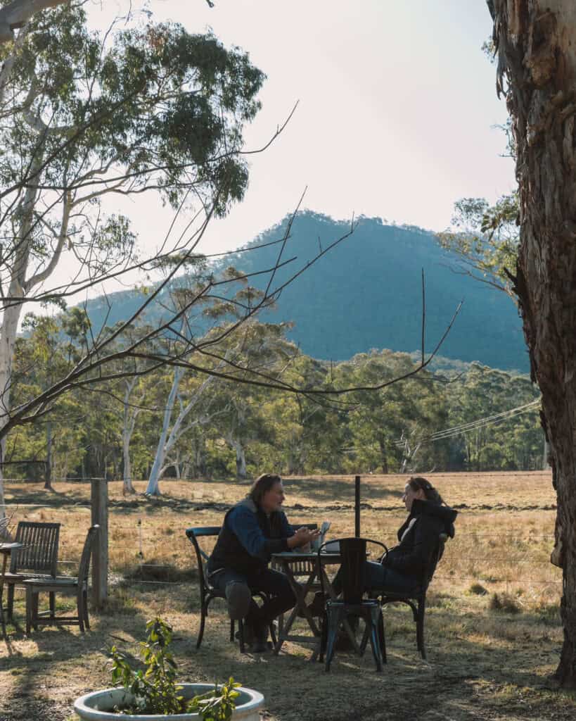 Two women enjoying tea outdoors in a scenic mountain setting.