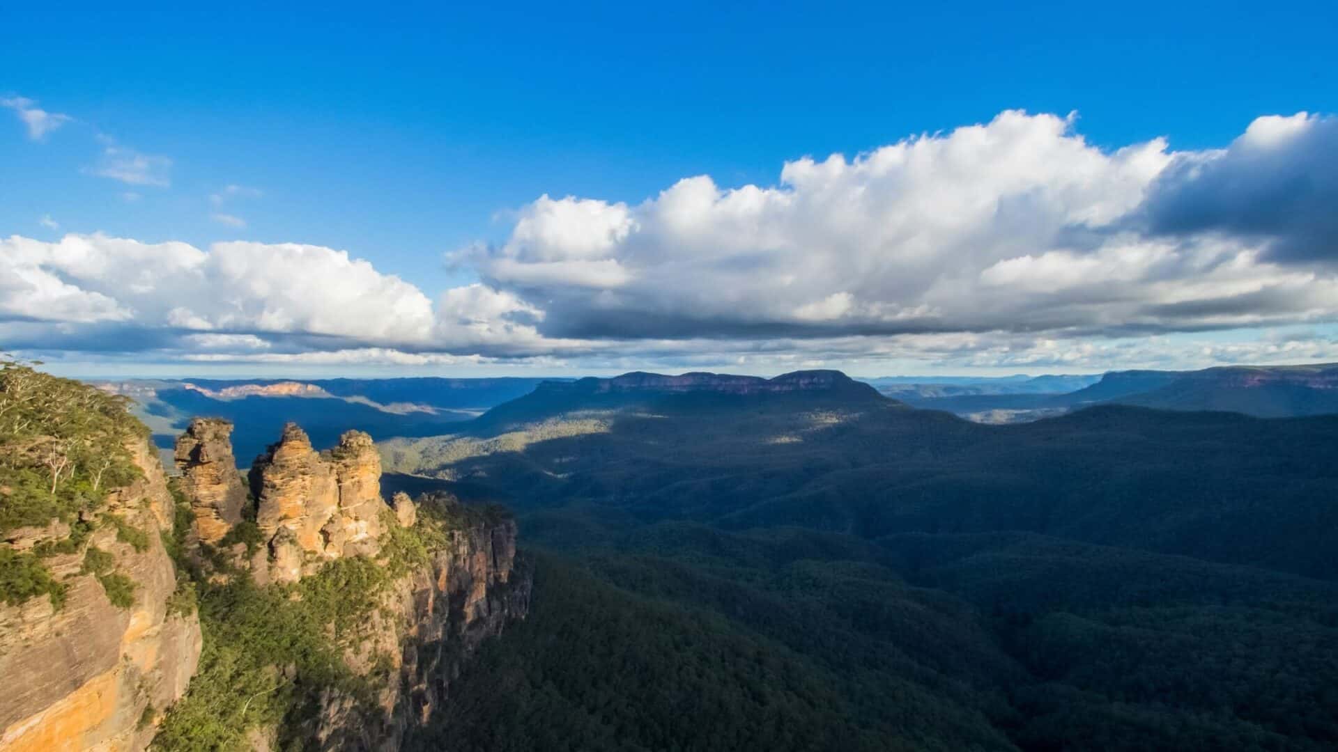 Scenic view of mountains and lush forests under a partly cloudy sky.