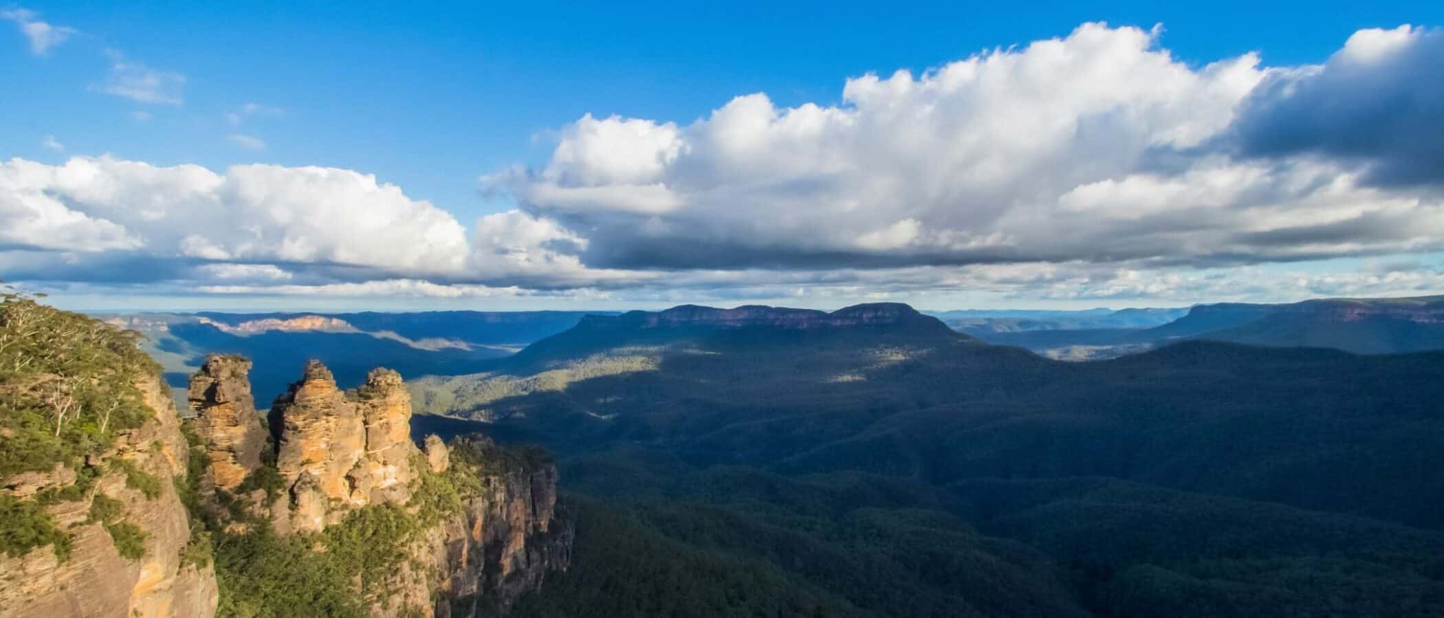 Scenic view of mountains and lush forests under a partly cloudy sky.