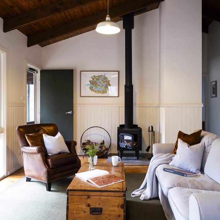 Comfortable living room with leather armchair, sofa, and wood stove for warmth and ambiance.