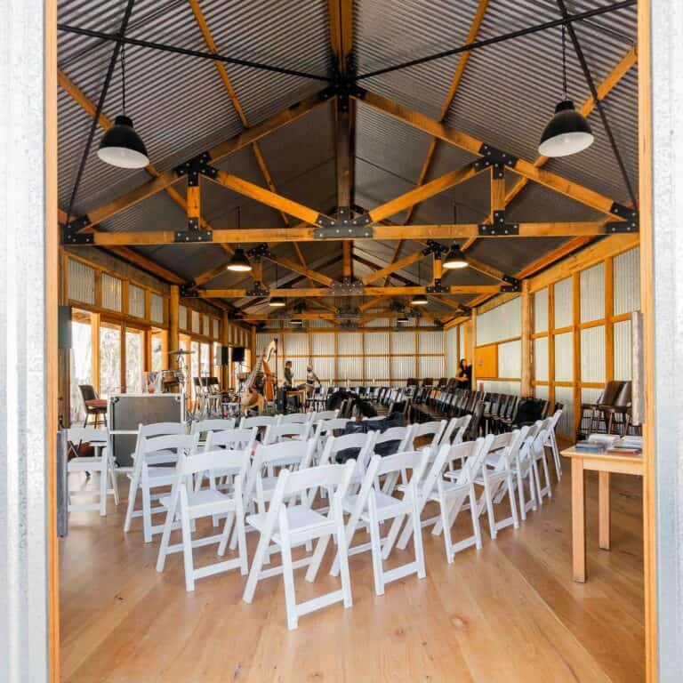 Indoor event space with white chairs and stage for wedding or function.
